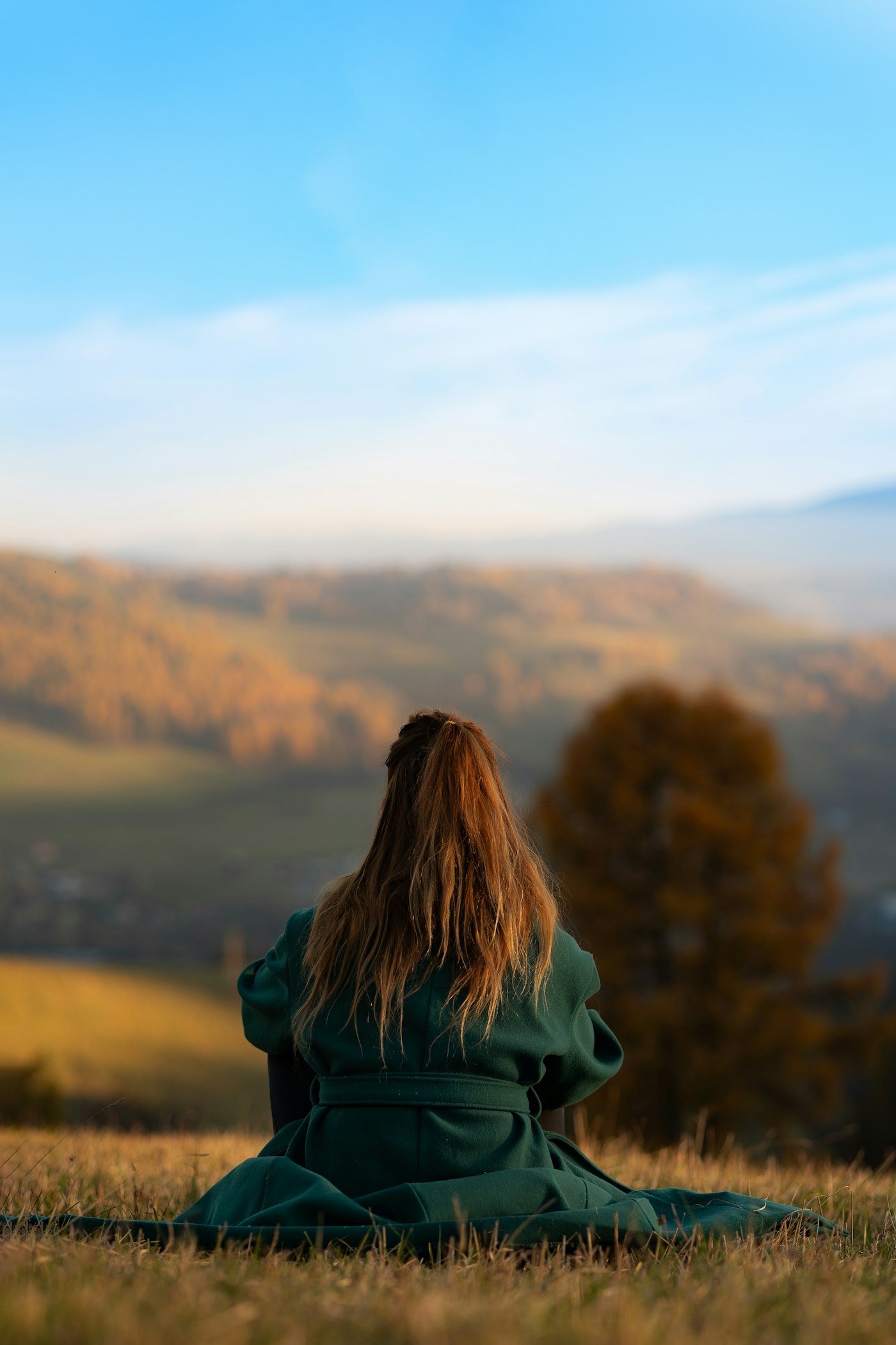 A person sitting quietly on a grassy hill
